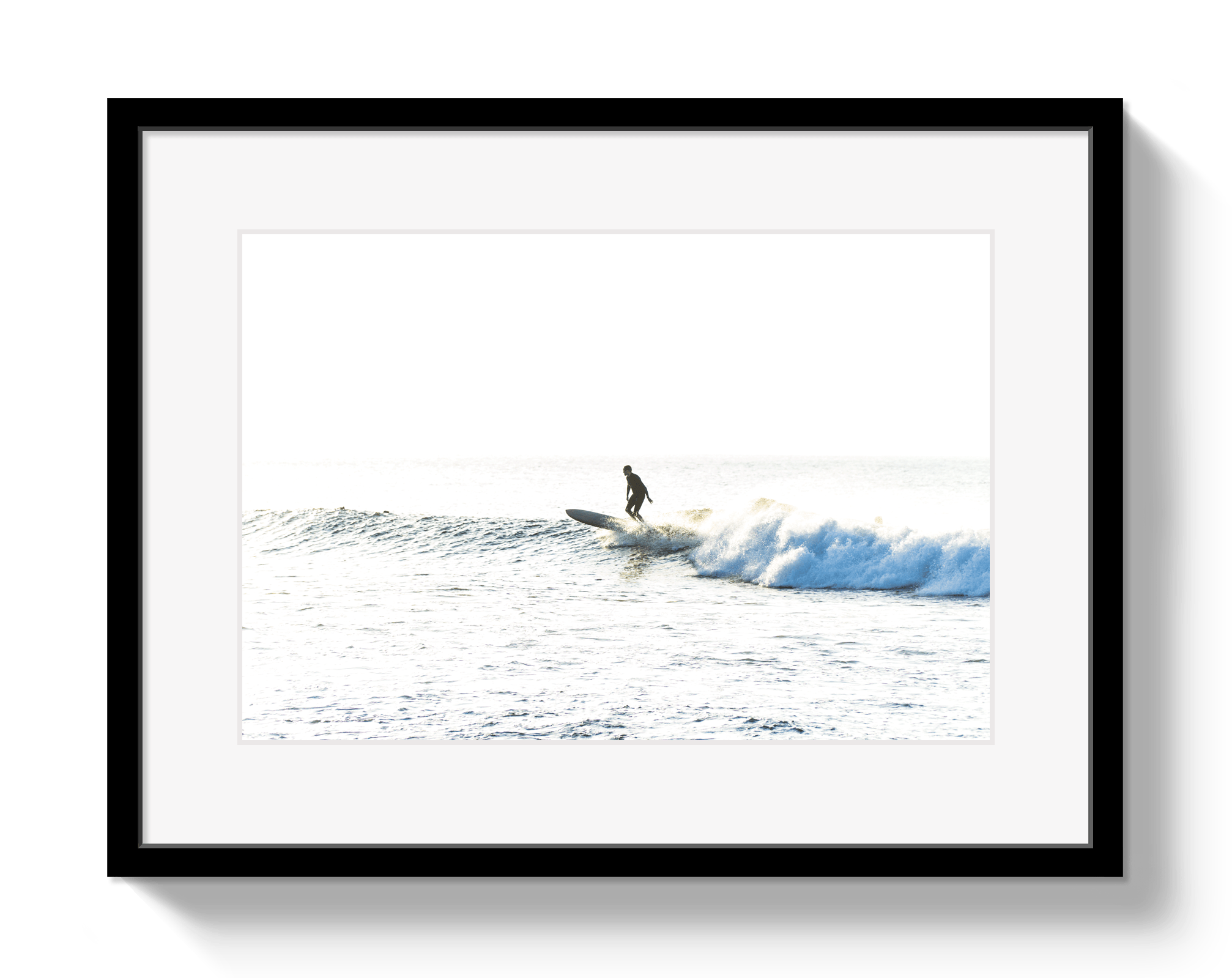 Framed photograph of a surfer riding a wave on a white background