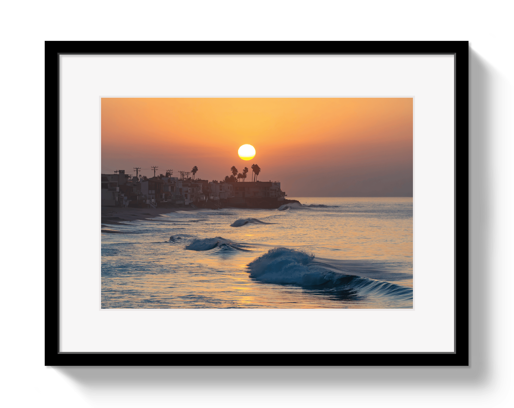 Framed artwork of a sunset over the ocean with a silhouette of buildings.