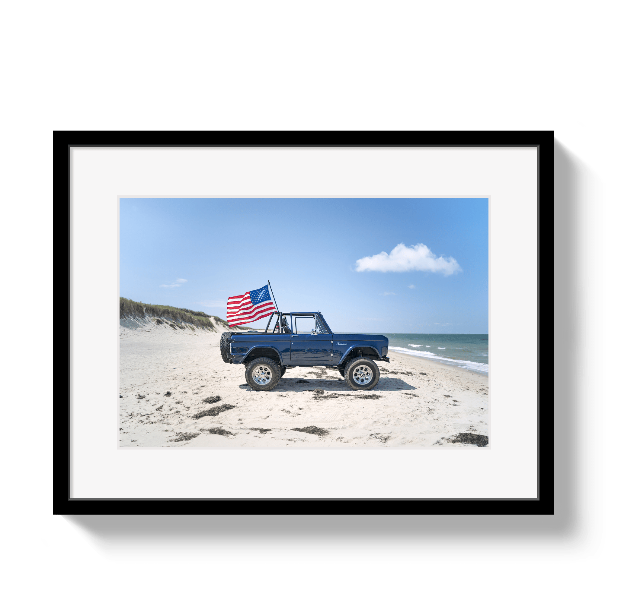 Framed photo of a blue truck with an American flag on a beach