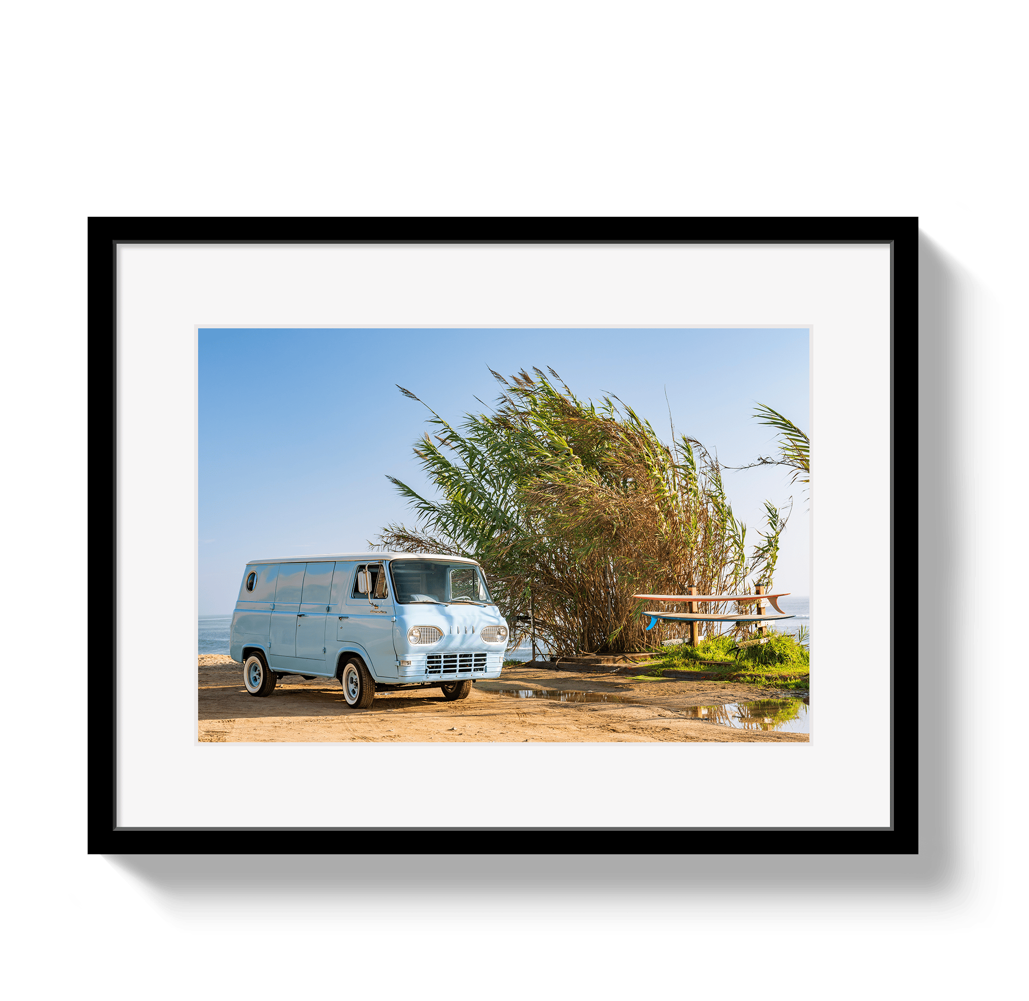 Framed photograph of a vintage van parked near tall grasses with a clear blue sky.