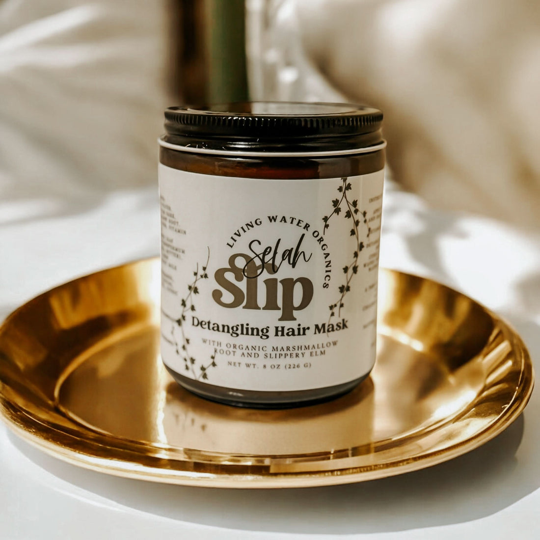 Jar of Selah Slip Detangling Hair Mask on a gold tray with a blurred background