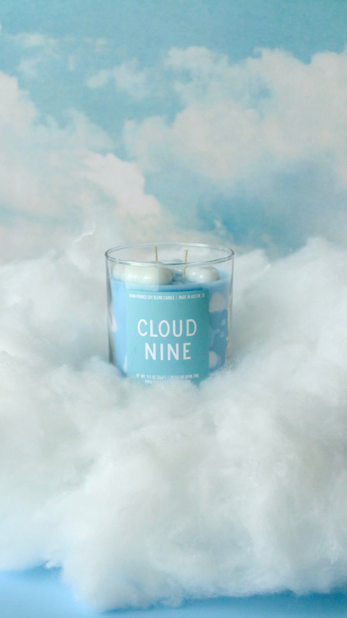 A blue candle in a clear glass jar with the words &