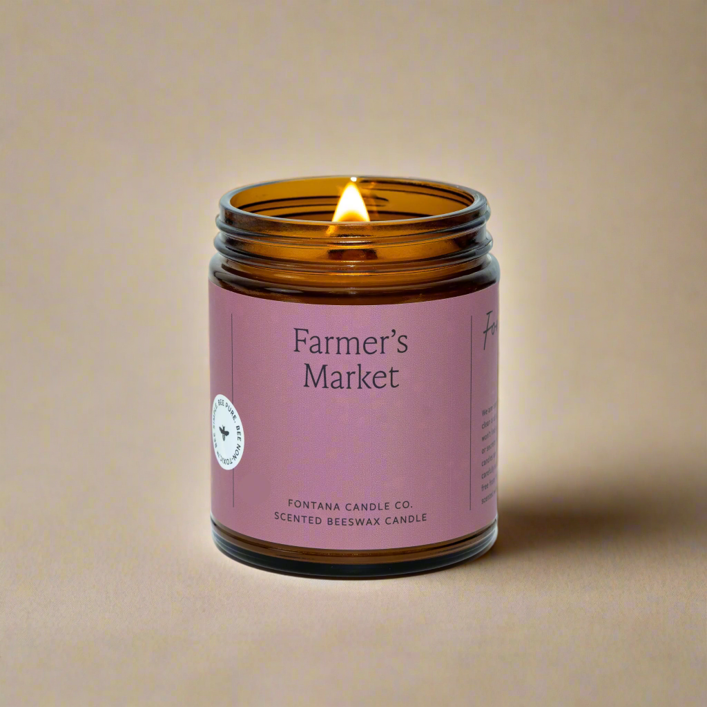 Beeswax candle in an amber glass jar with a pink label on a white background