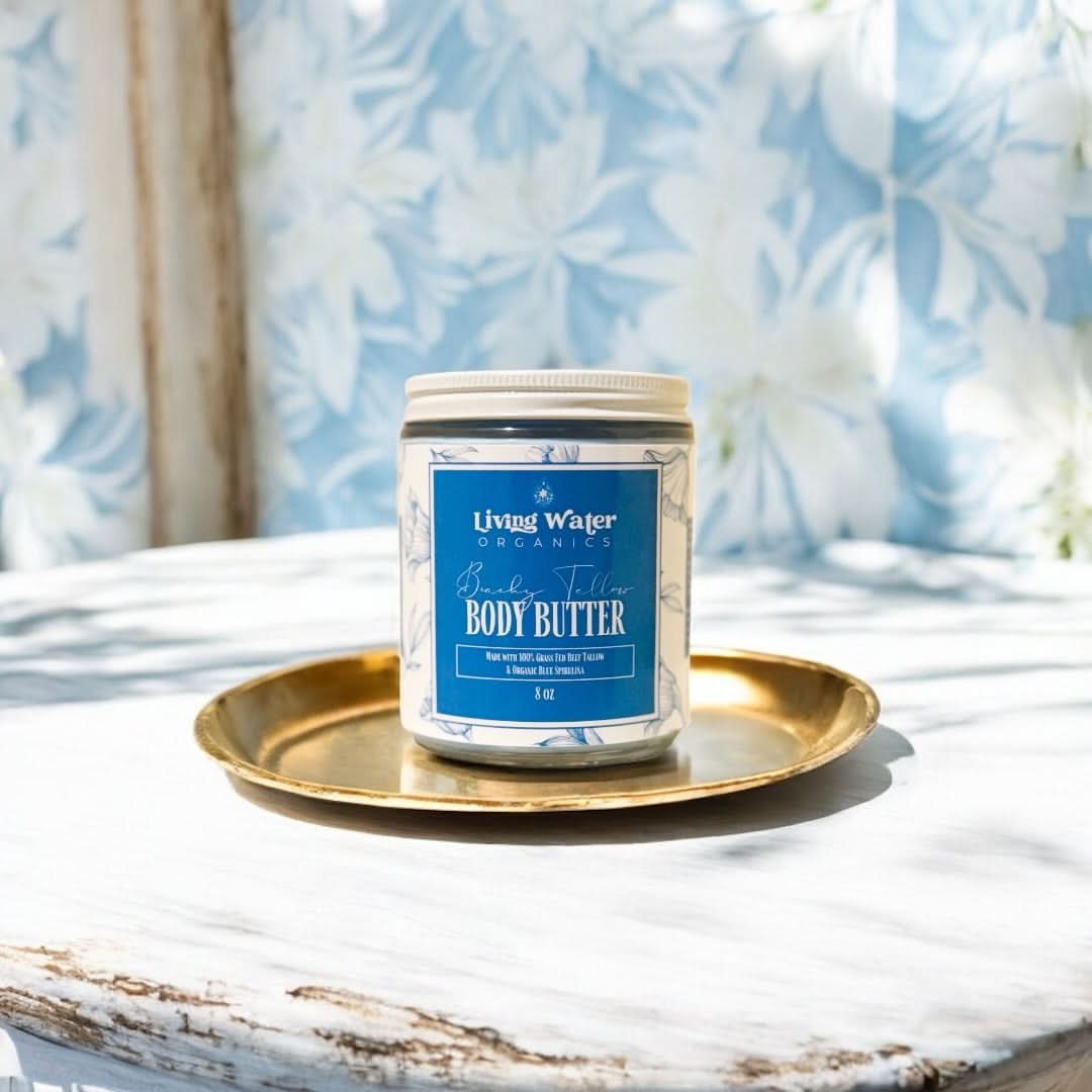 Living Water Organics body butter jar on a gold tray with a floral curtain background
