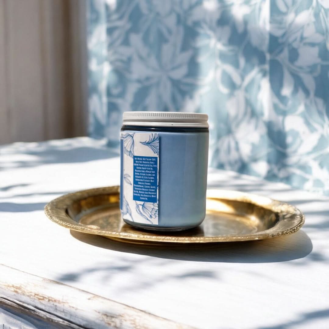 Candle with decorative label on a gold tray against a light background