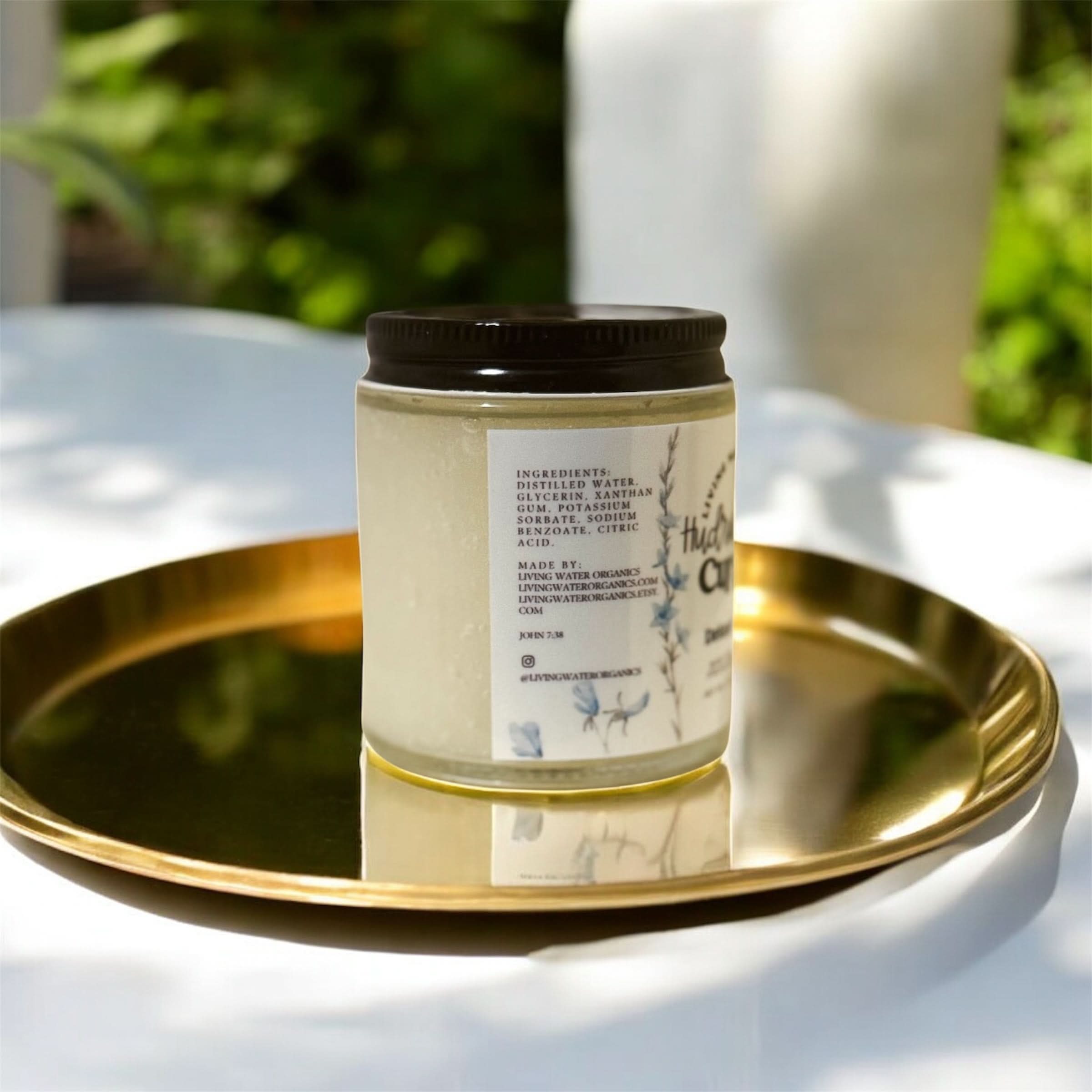 Candle jar on a gold tray with a blurred green outdoor background