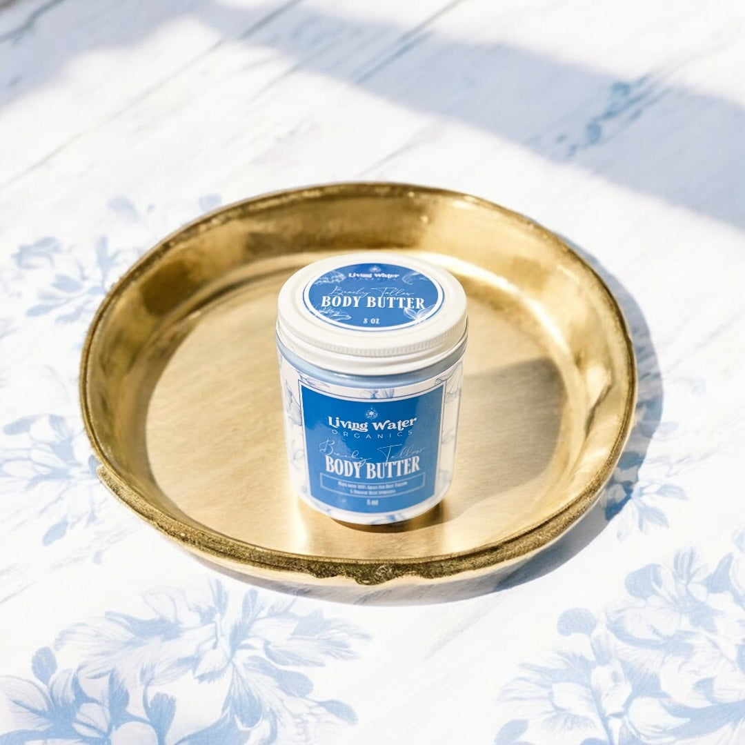 Jar of body butter on a gold tray with a blue label against a light floral background