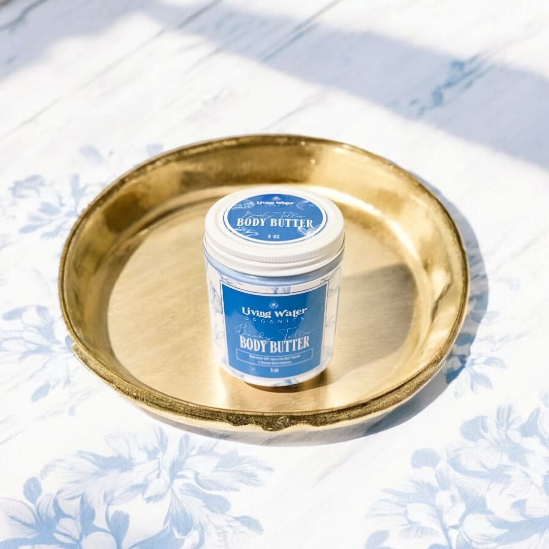 Jar of body butter on a gold tray with a blue label against a light floral background