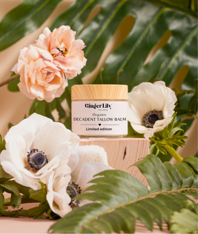 Ginger Lily organic decadent tallow balm with flowers and green leaves in the background