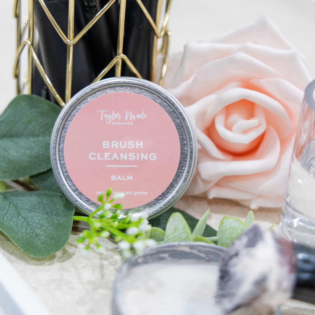 Taylor Made Brush Cleansing Balm container with a rose and makeup brush on a decorative background