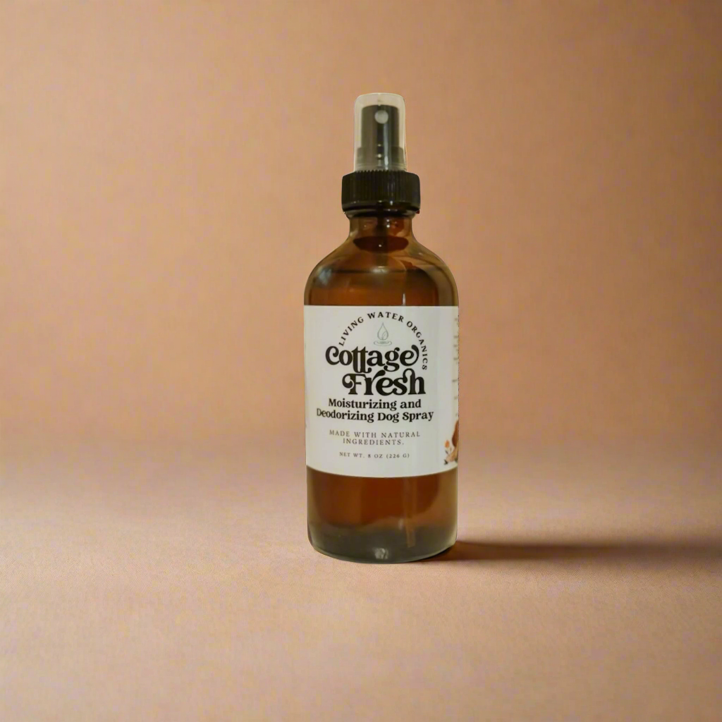 Bottle of Cottage Fresh body spray on a gold tray with white flowers in the background