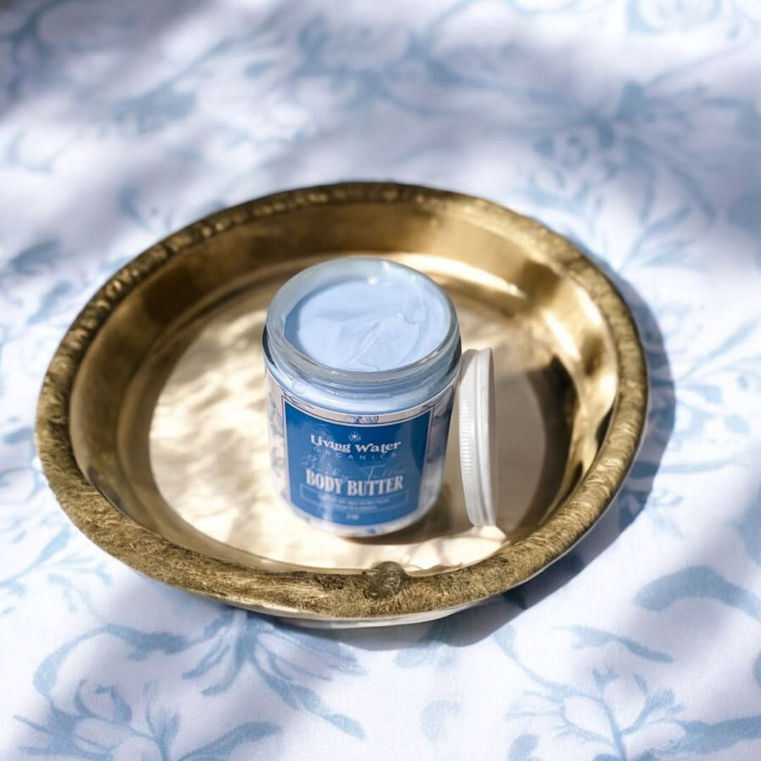 Jar of body butter on a gold tray with a floral patterned background