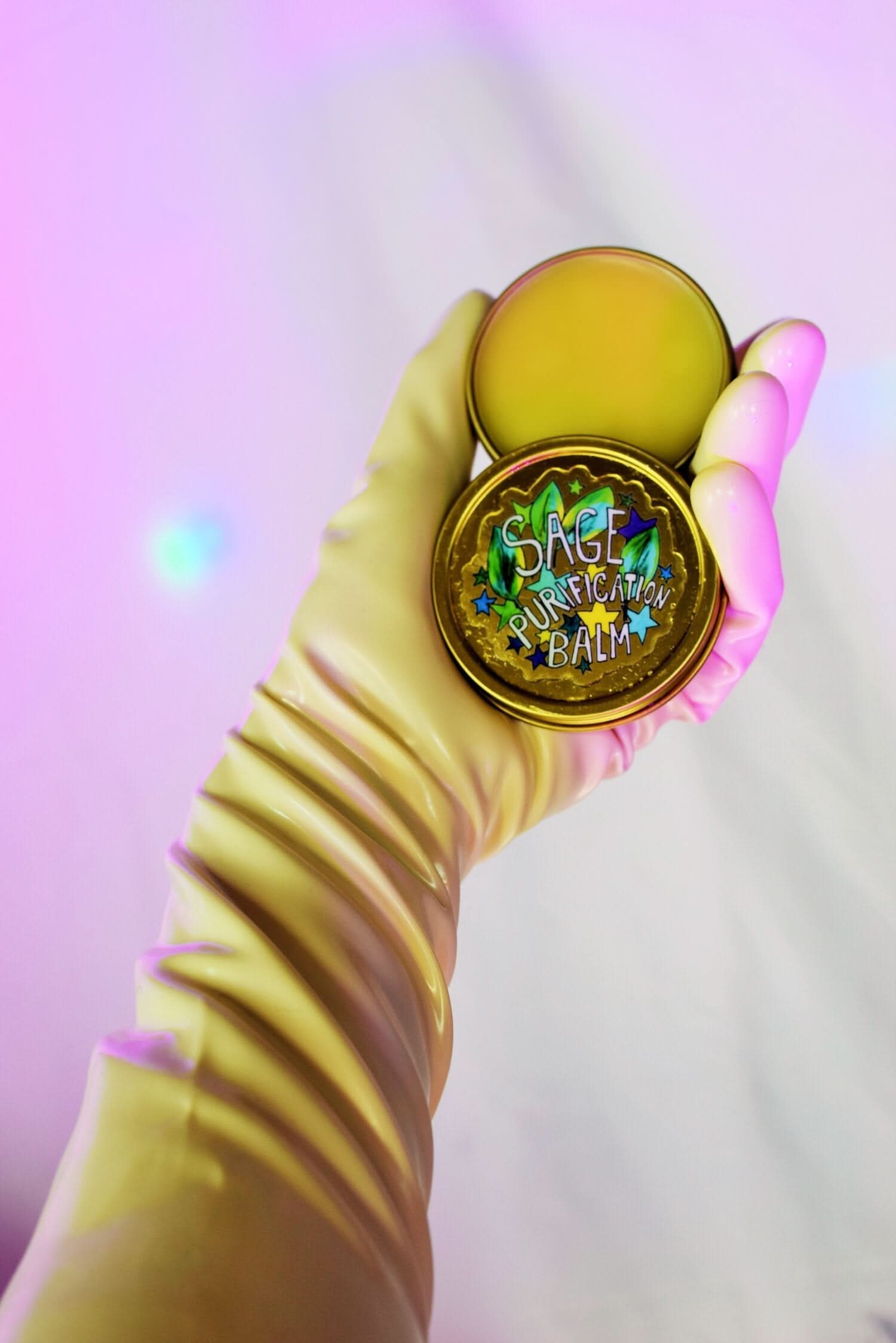 Hand holding a round, gold-colored product with &