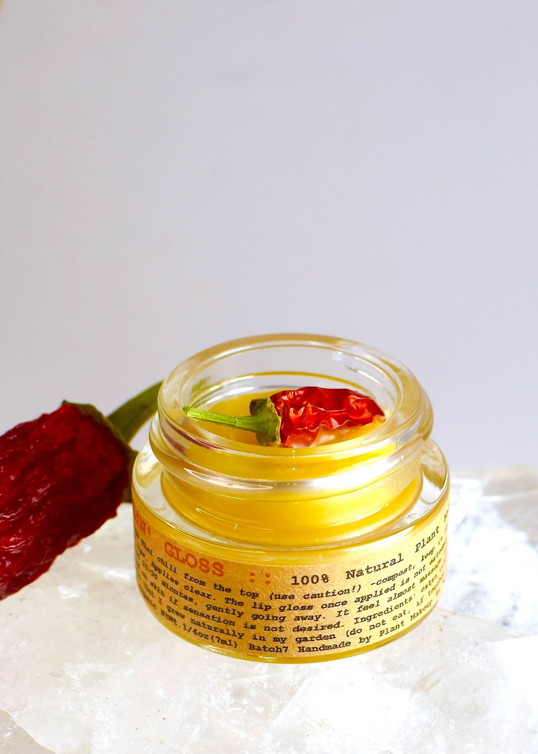 Jar of natural product with chili peppers on a white background