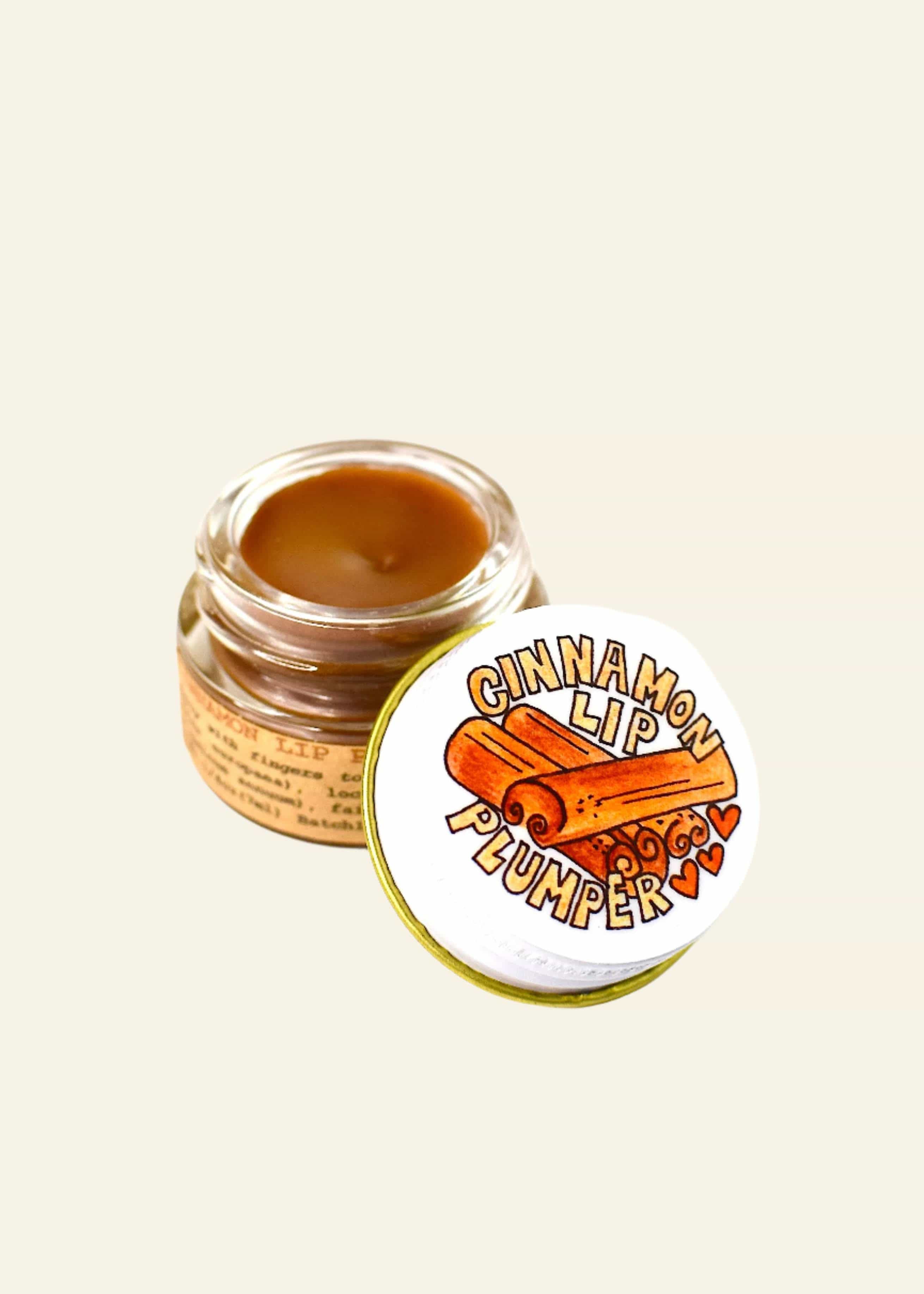 Jar of cinnamon lip balm with a matching lip balm on a white background