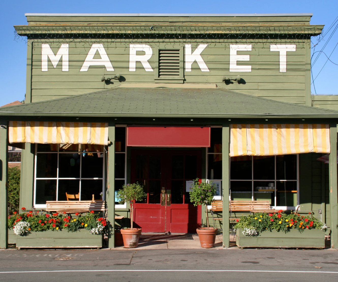 Green market building with 'MARKET' sign and flower boxes.