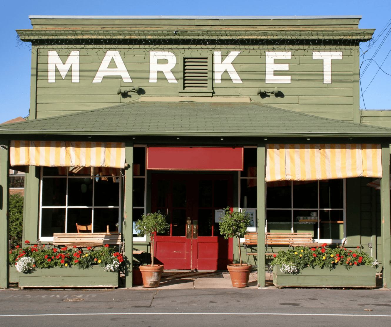 Green market building with 'MARKET' sign and flower boxes.