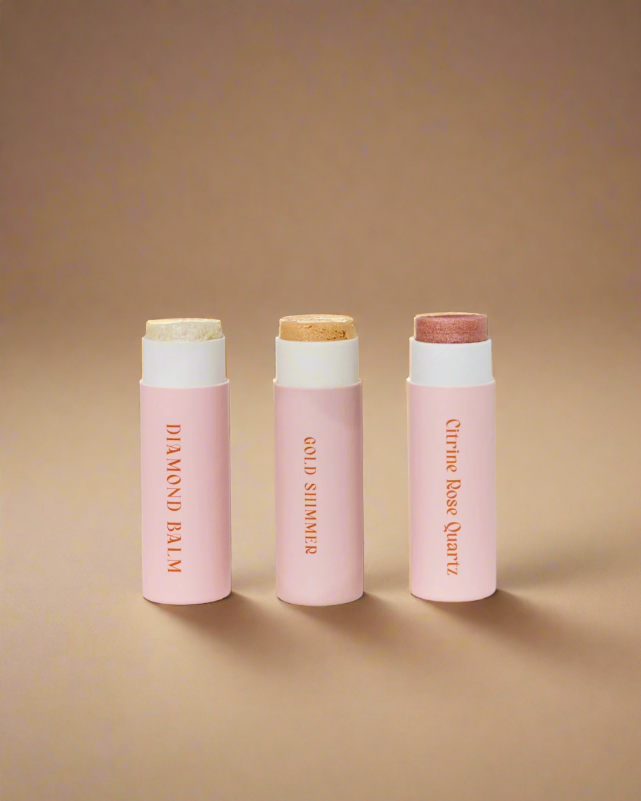 Three pink lip balm tubes with white caps on a light gray background
