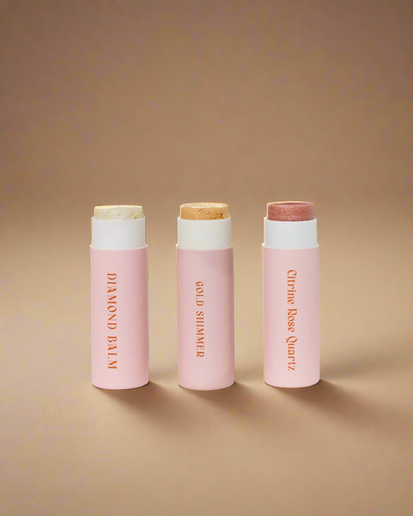 Three pink lip balm tubes with white caps on a light gray background