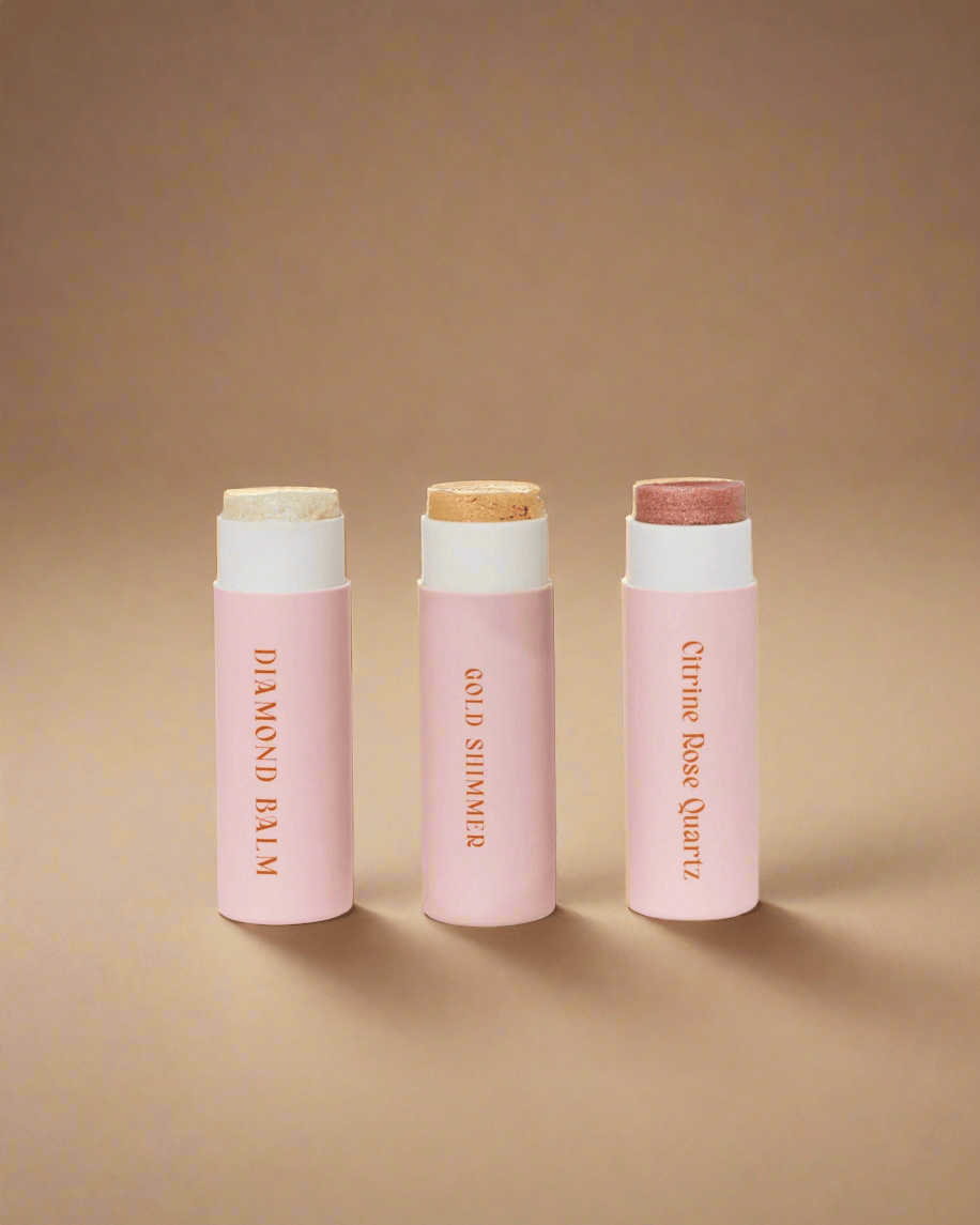 Three pink lip balm tubes with white caps on a light gray background