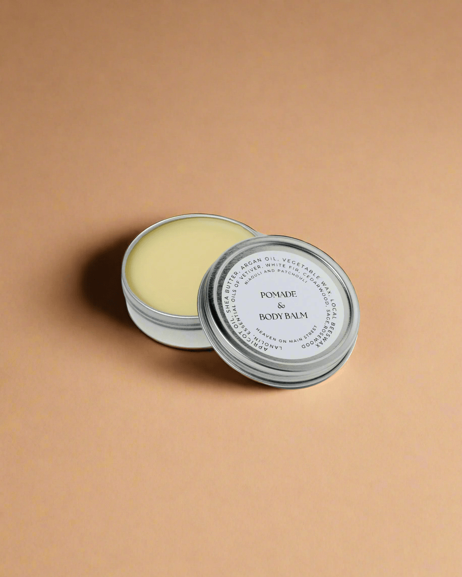 Body balm in a metal tin with a white label on a light gray background
