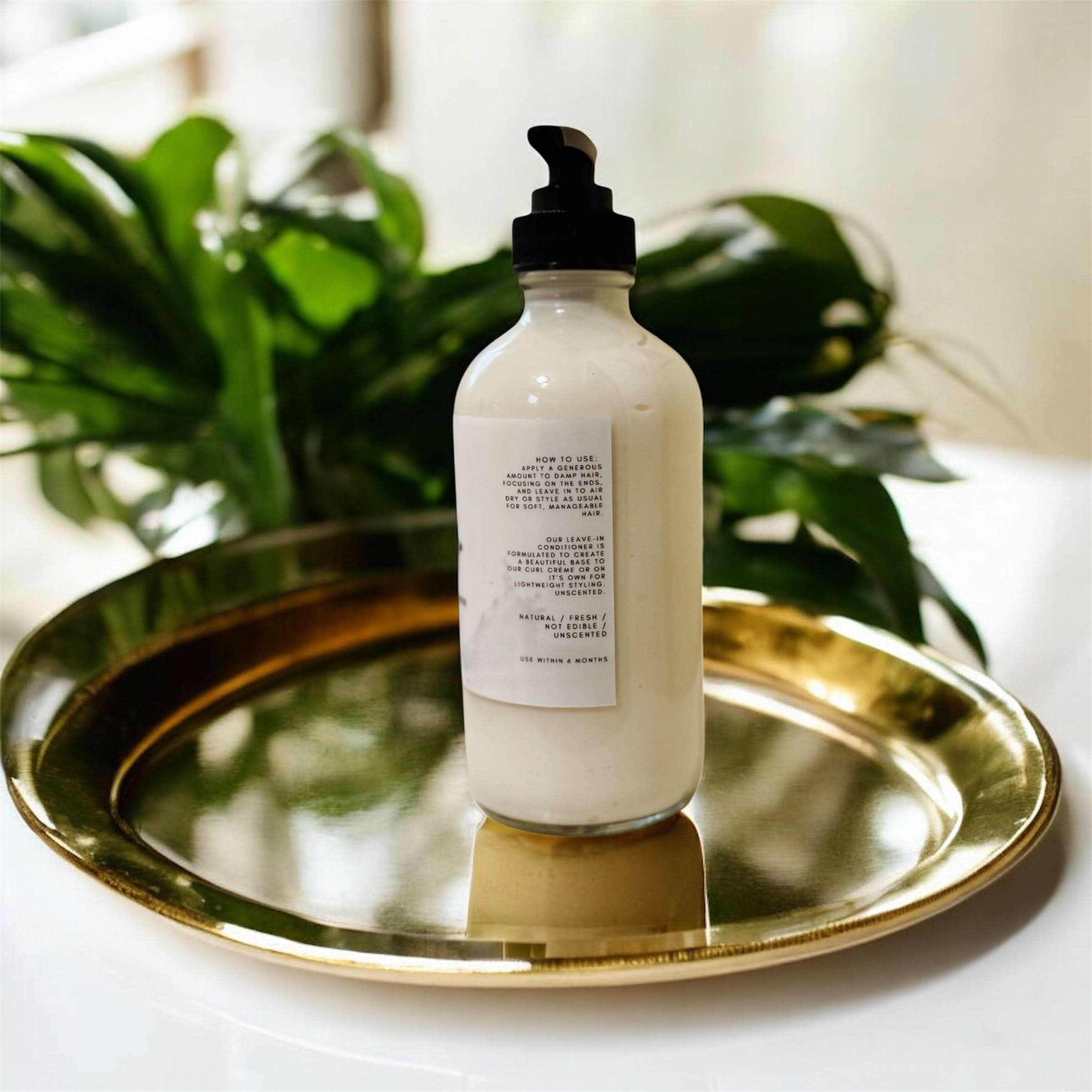 White bottle with black pump on a gold tray with green plants in the background