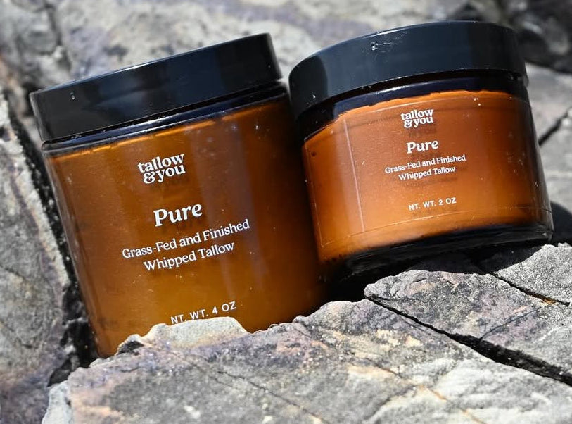 Two jars of tallow & you Pure on a stone surface with promotional text.