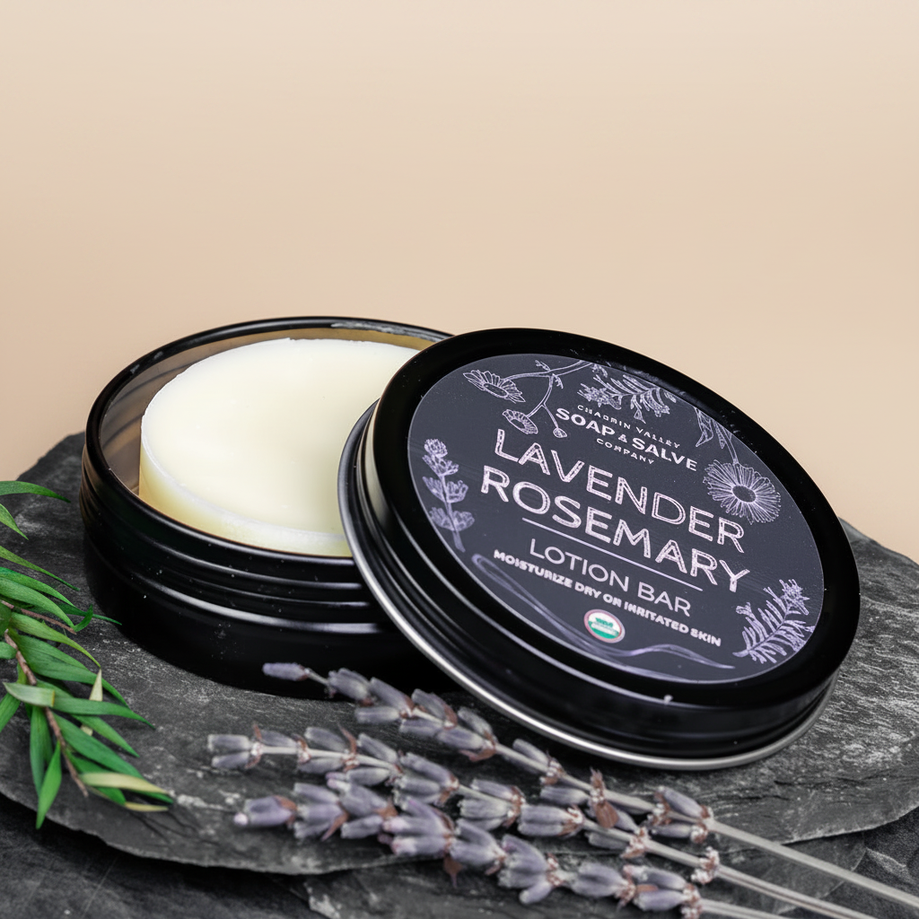 An open round black tin of Lavender Rosemary lotion bar with the lid leaning beside it, styled on a dark stone surface with lavender sprigs, a wooden bowl, and a soap dish.