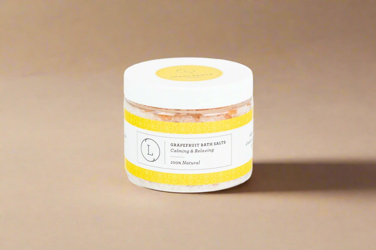Jar of grapefruit bath salts with a yellow label on a beige background