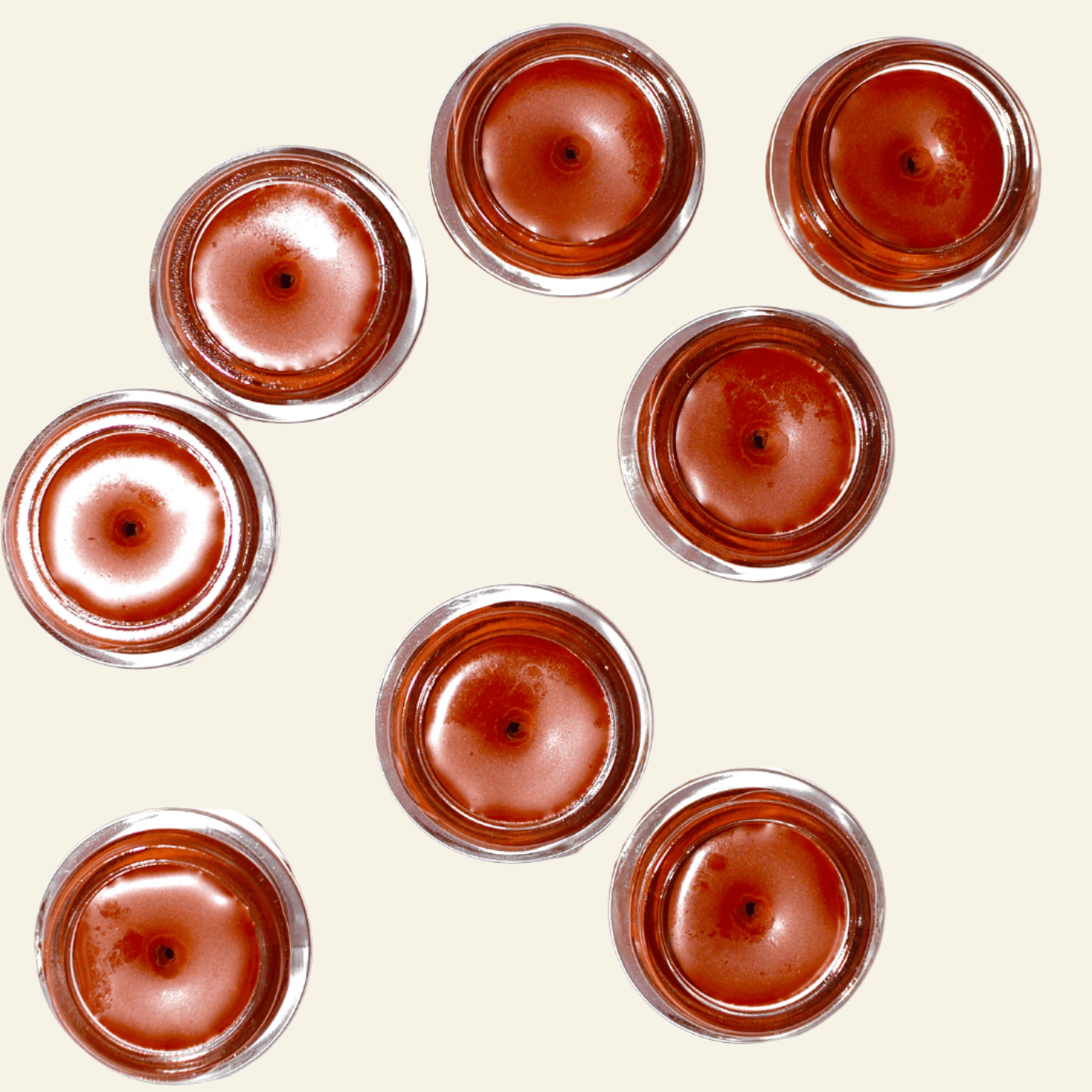 Nine small jars with a brownish-red substance on a white background