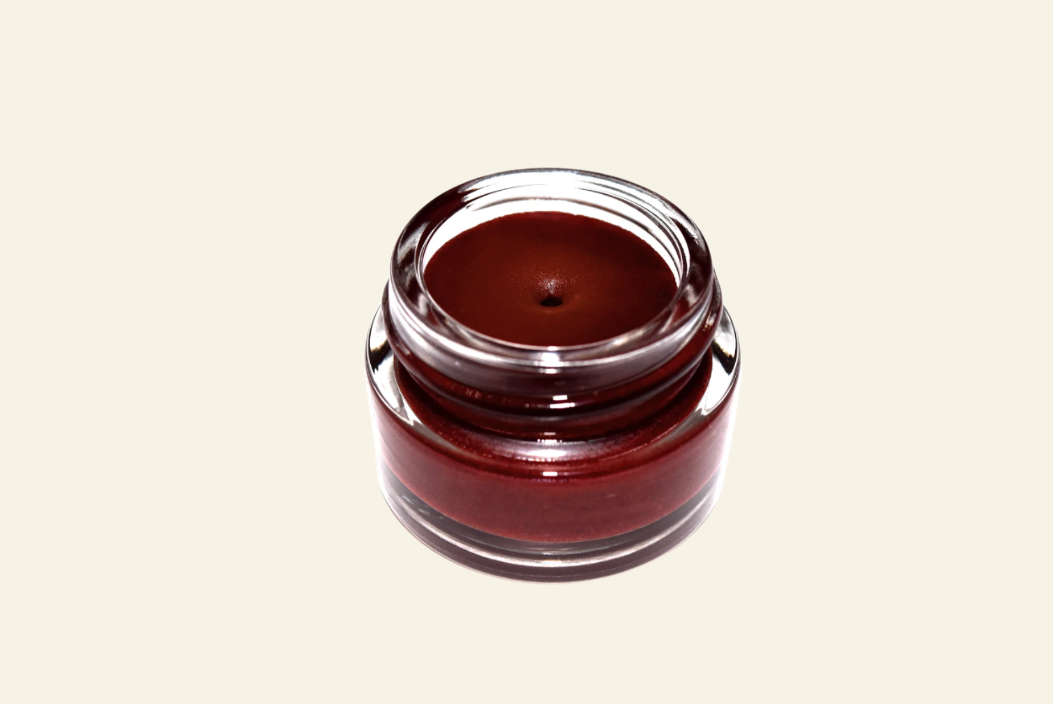 Small jar of dark brown cream on a white background