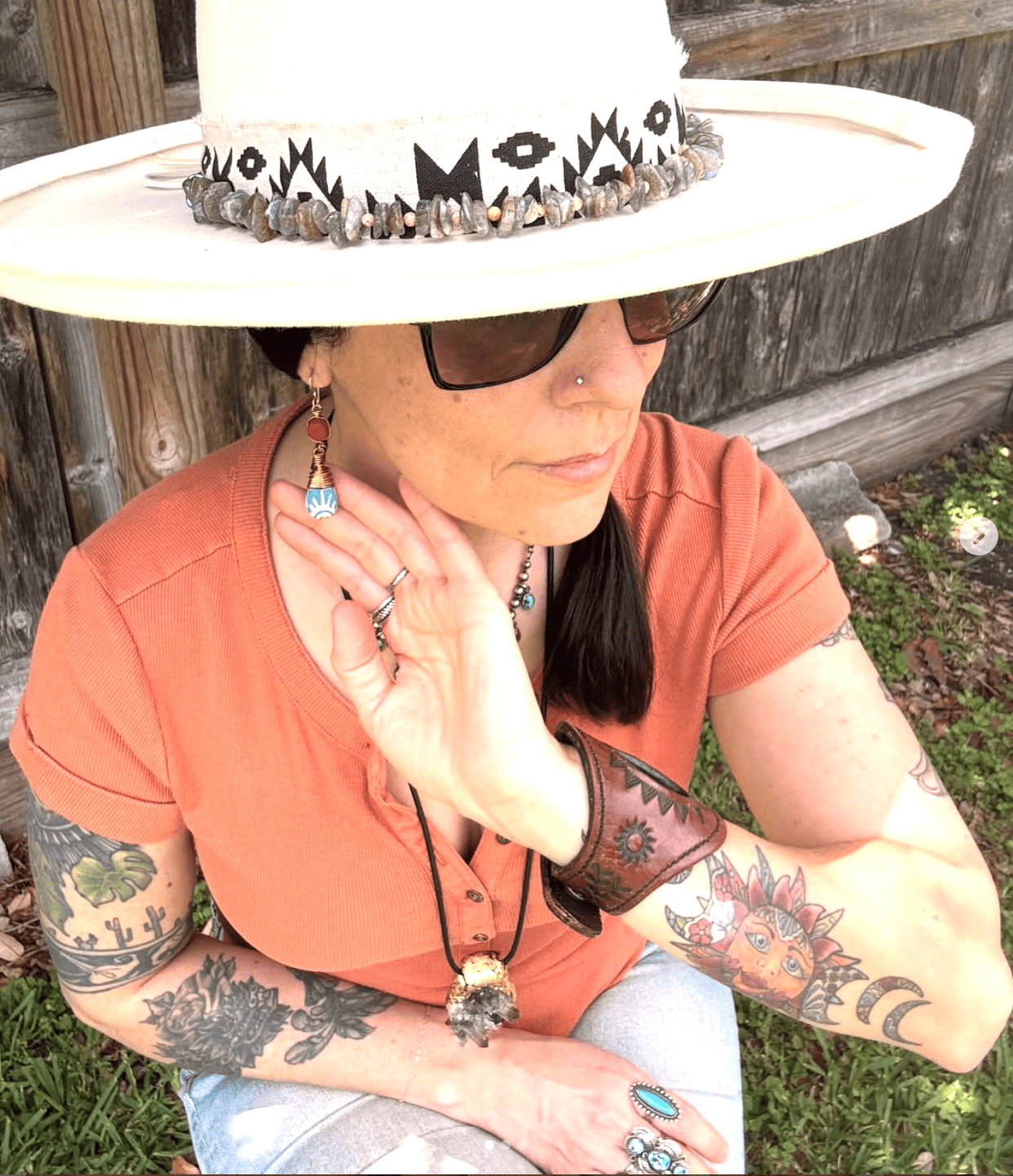 Person wearing a wide-brimmed hat with decorative band, sitting outdoors.