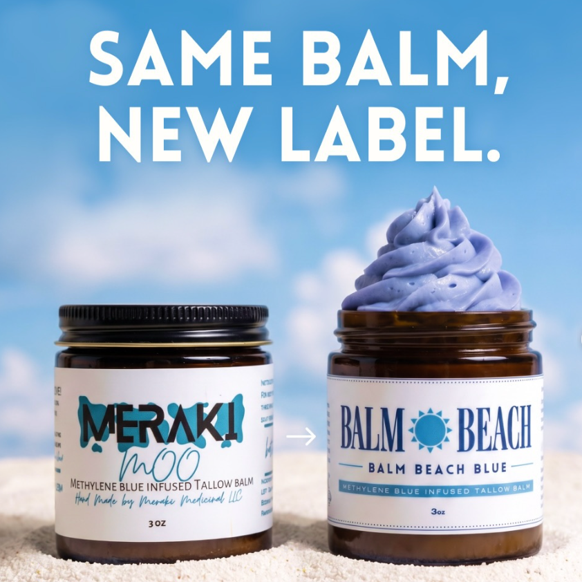 Two amber balm jars on a sandy surface with a blue sky background. The left jar has a black lid and a white label reading MERAKI NaNo, and the right jar has a blue lid and a white label reading Balm Beach Balm Beach Blue, with a swirl of lavender-blue balm displayed above it.