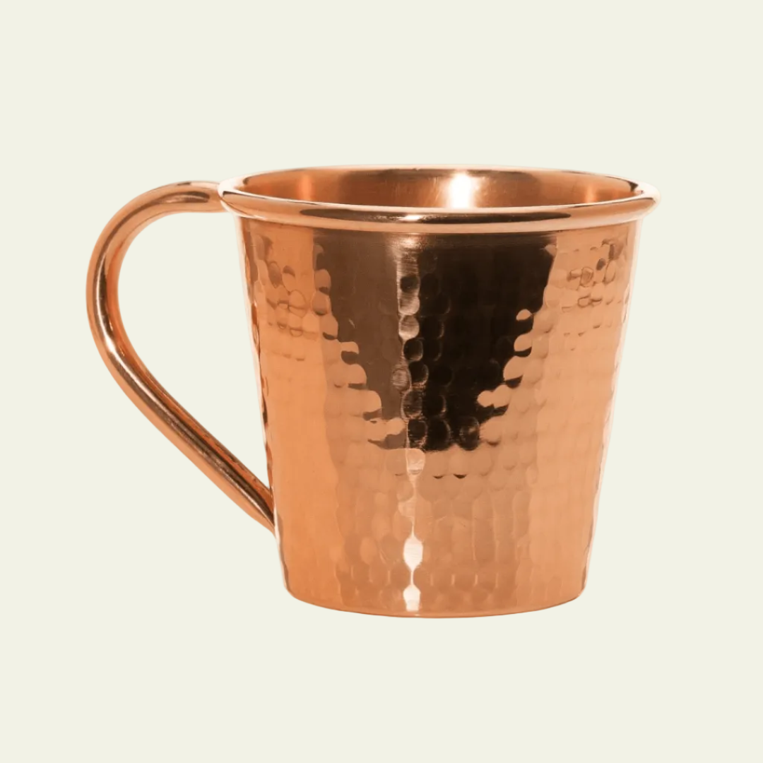 Copper mug with a textured surface on a light beige background