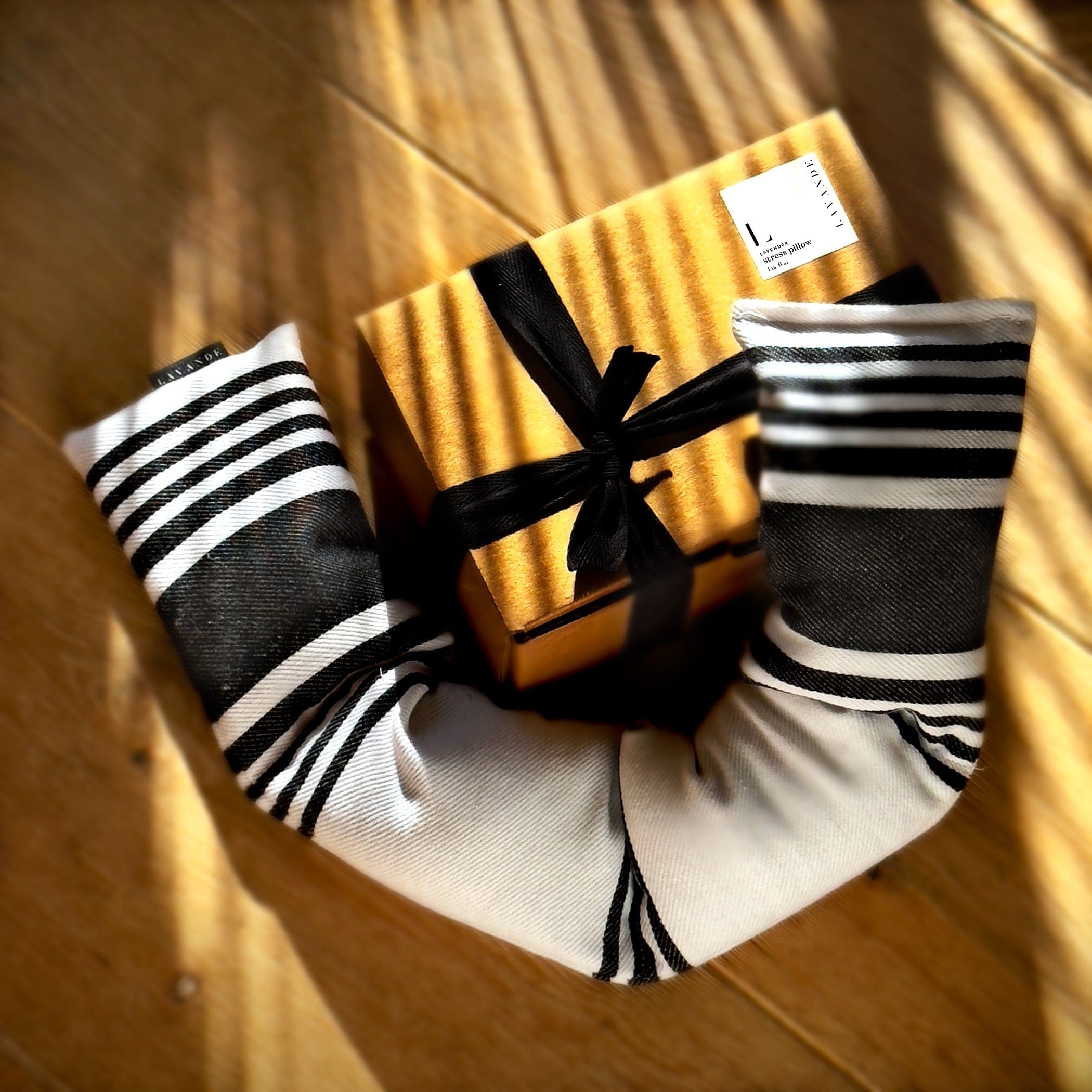 Gift box with black ribbon and two black and white striped socks on a wooden surface