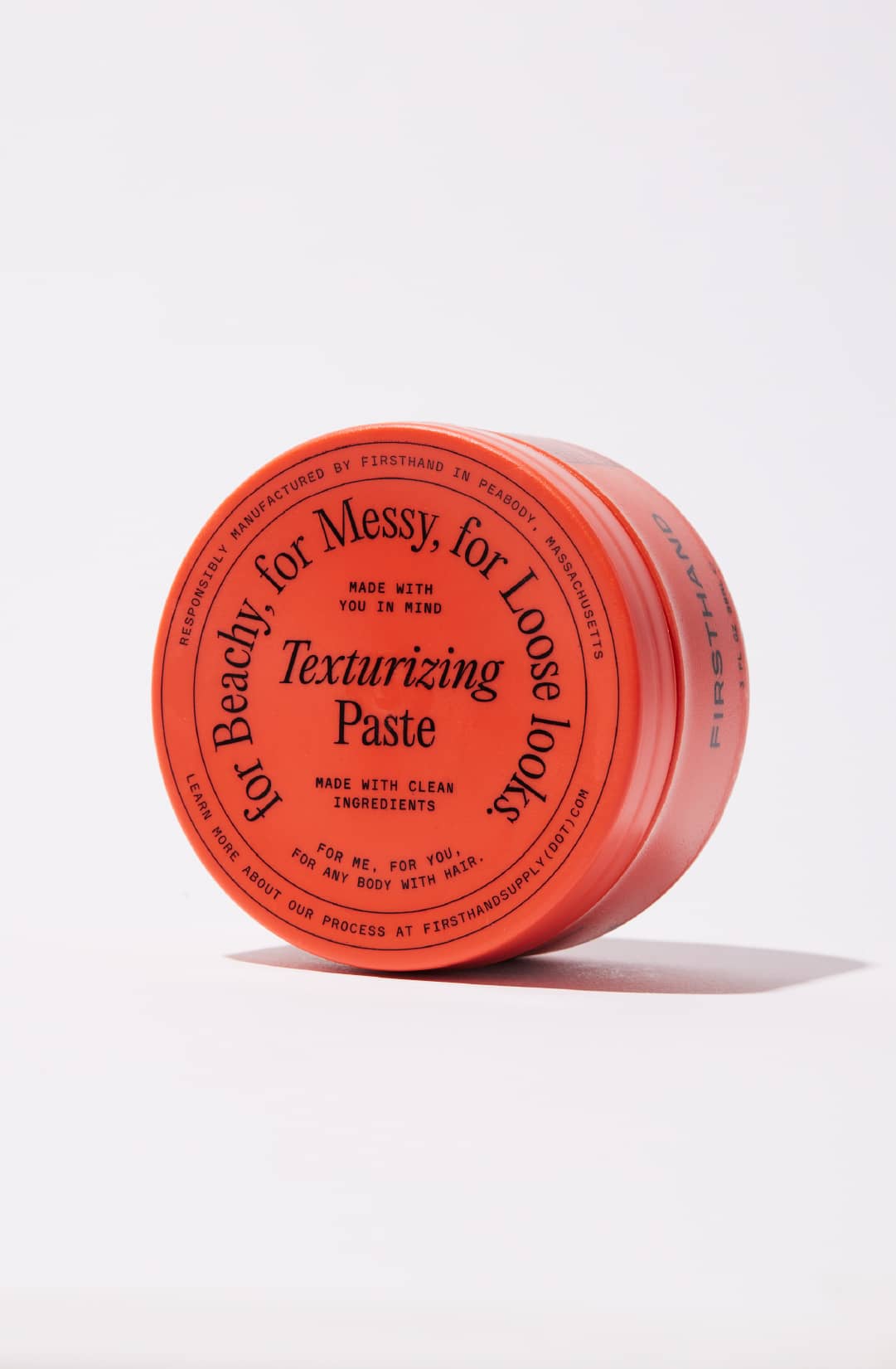 Red container of texturizing paste with black text on a white background