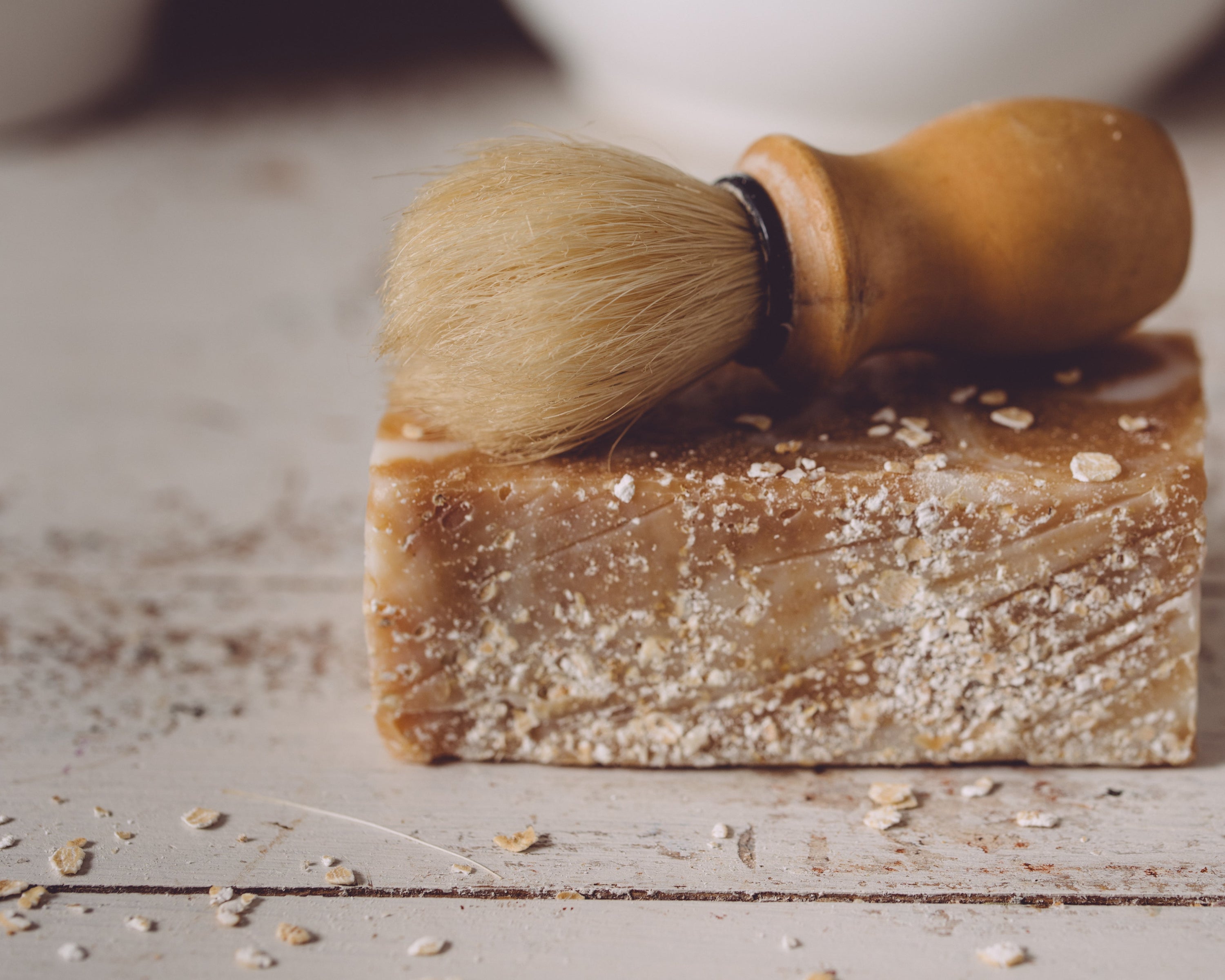Bar of soap with a brush on top on a wooden surface
