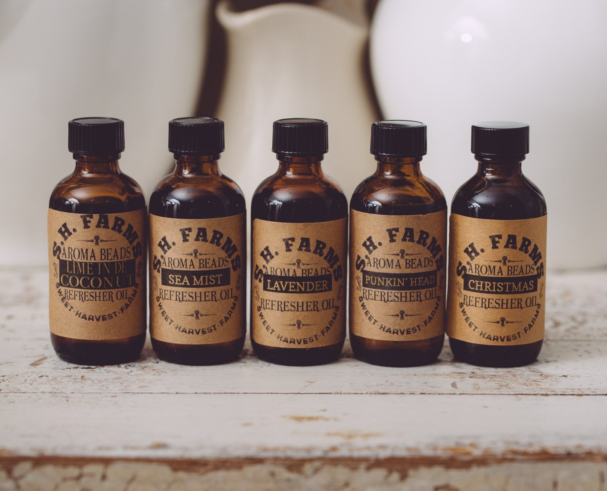 Five bottles of H. Farm Aroma Beads on a rustic surface with a blurred background.