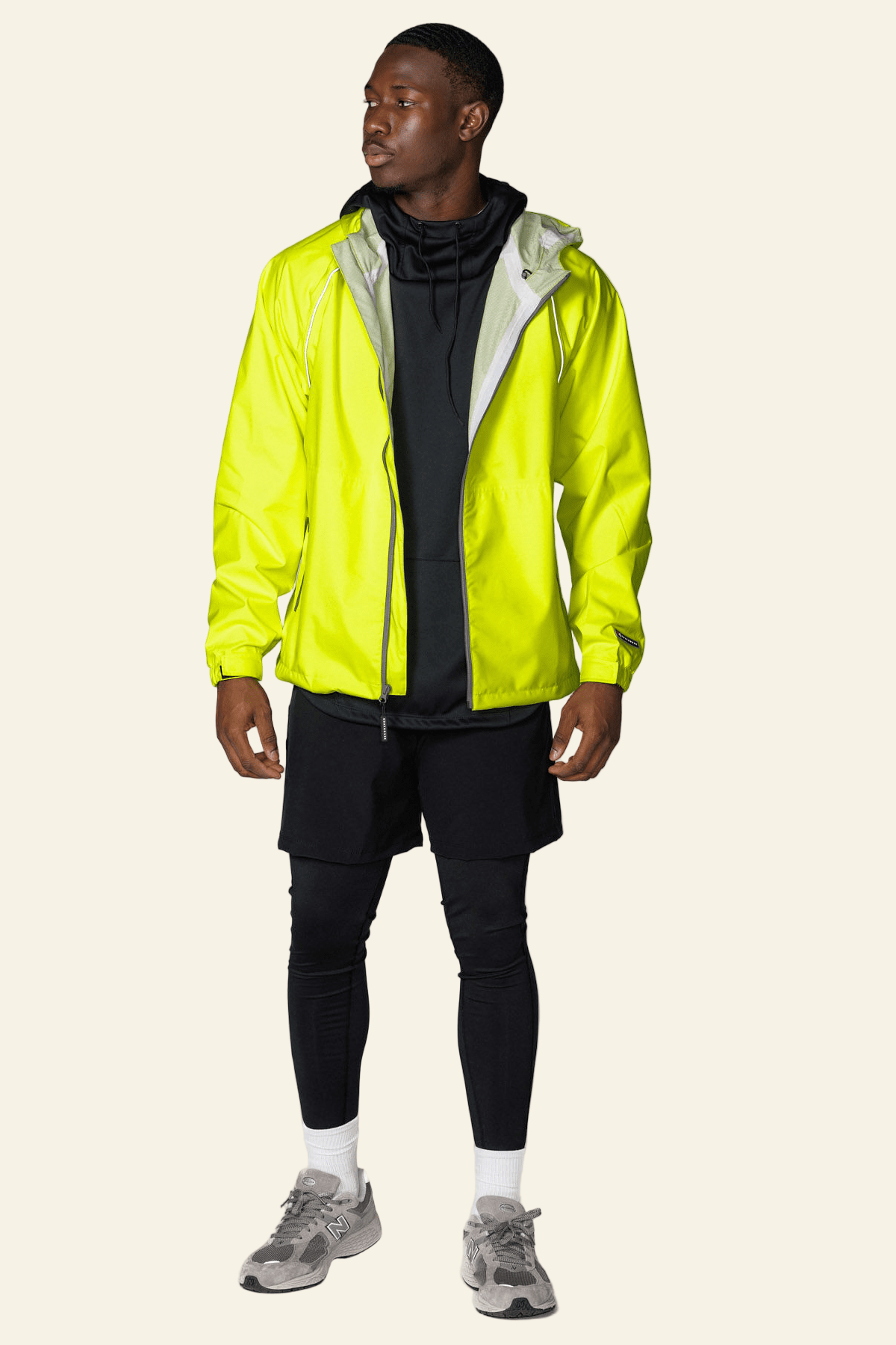 Person wearing a bright yellow raincoat over a black outfit on a white background