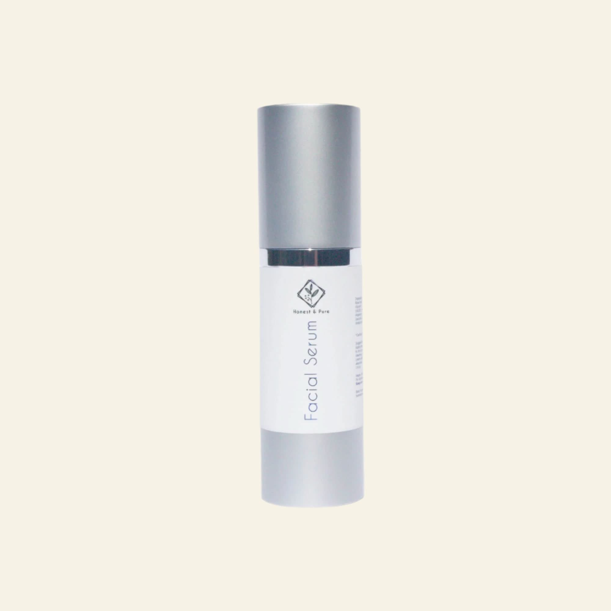 Facial serum bottle with silver cap and white body on a light gray background