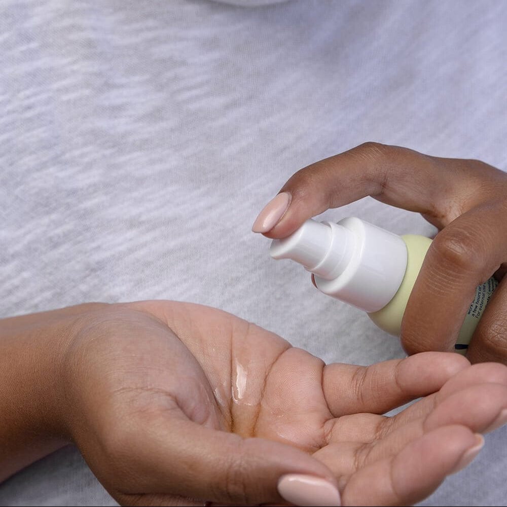 Person applying a small bottle of lotion to their hand