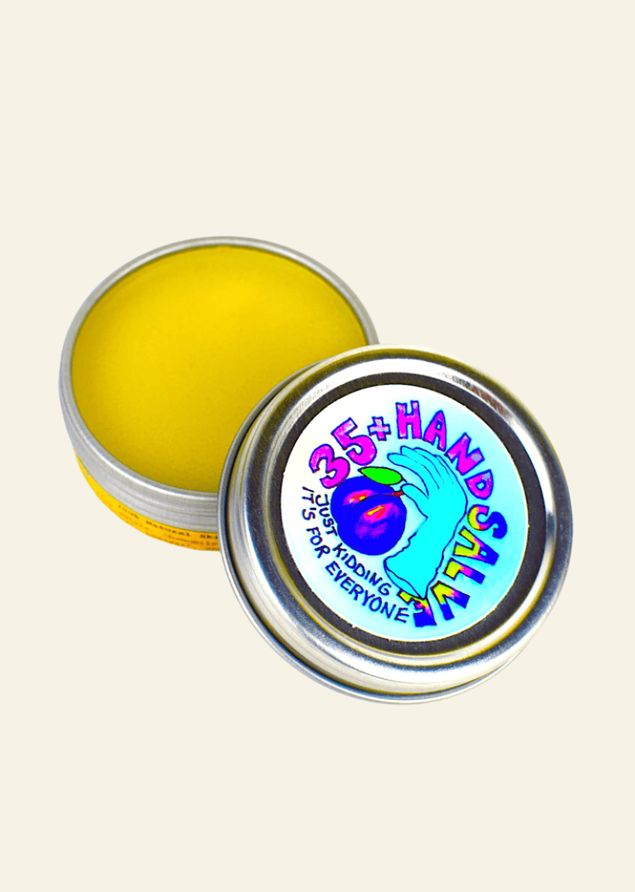 Yellow hand salve in a tin with a colorful label on a white background