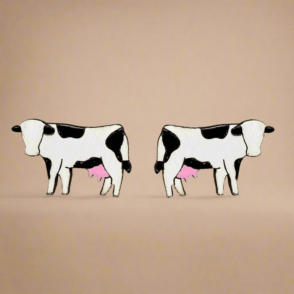 Two black and white cow earrings with pink udders on a beige background
