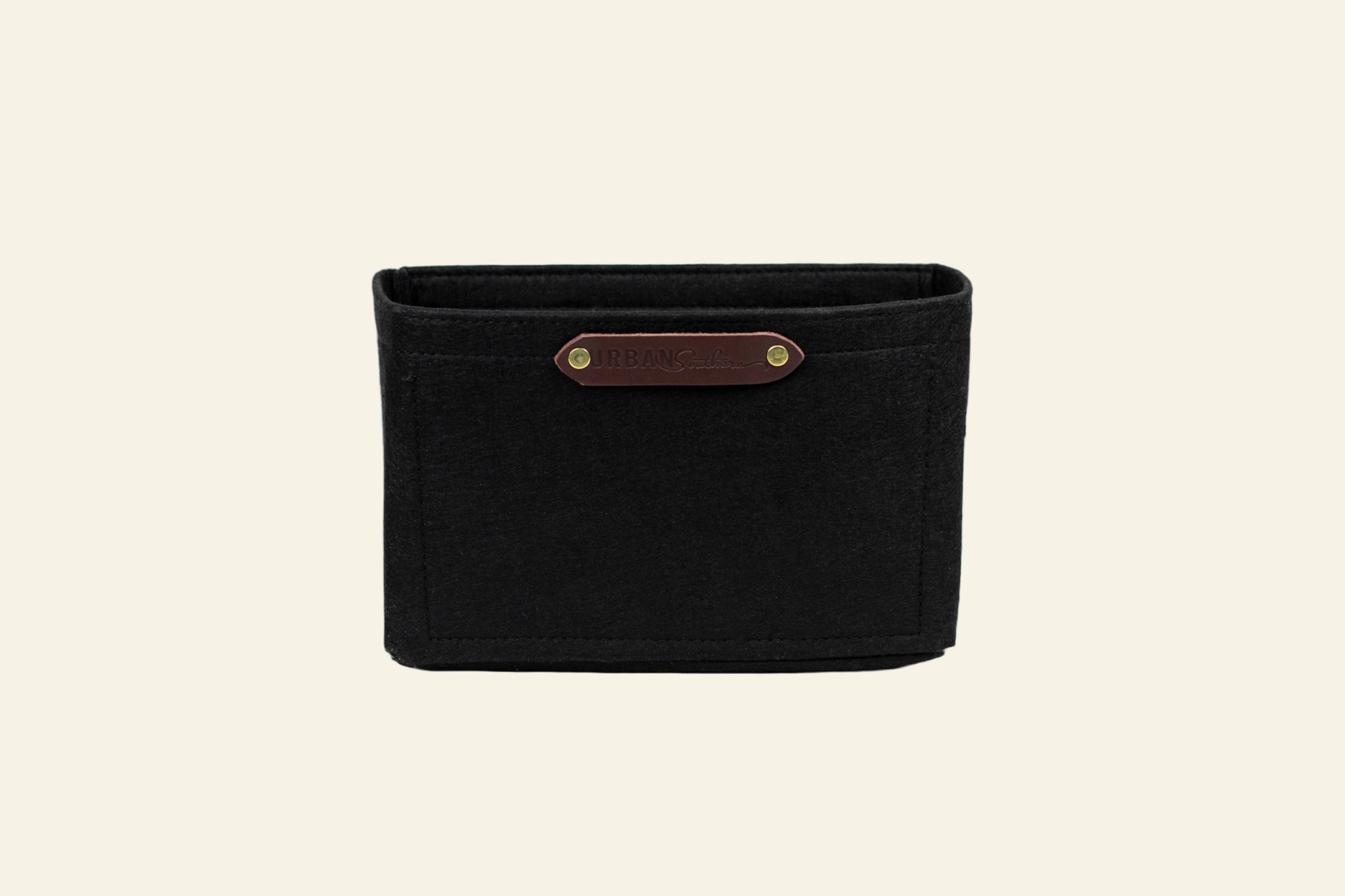 Black woven basket with a brown leather strap on a white background