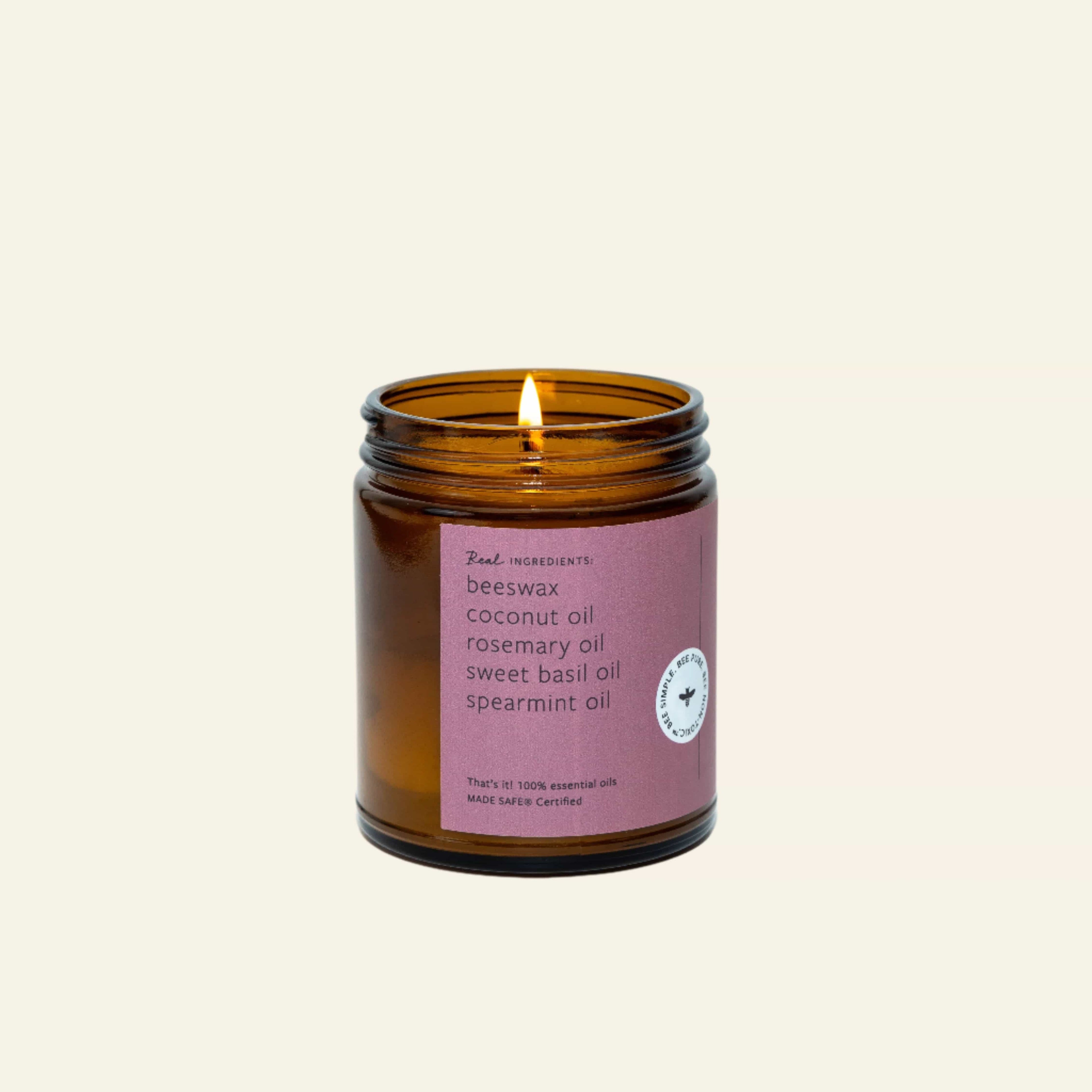 Candle in an amber jar with a purple label on a white background
