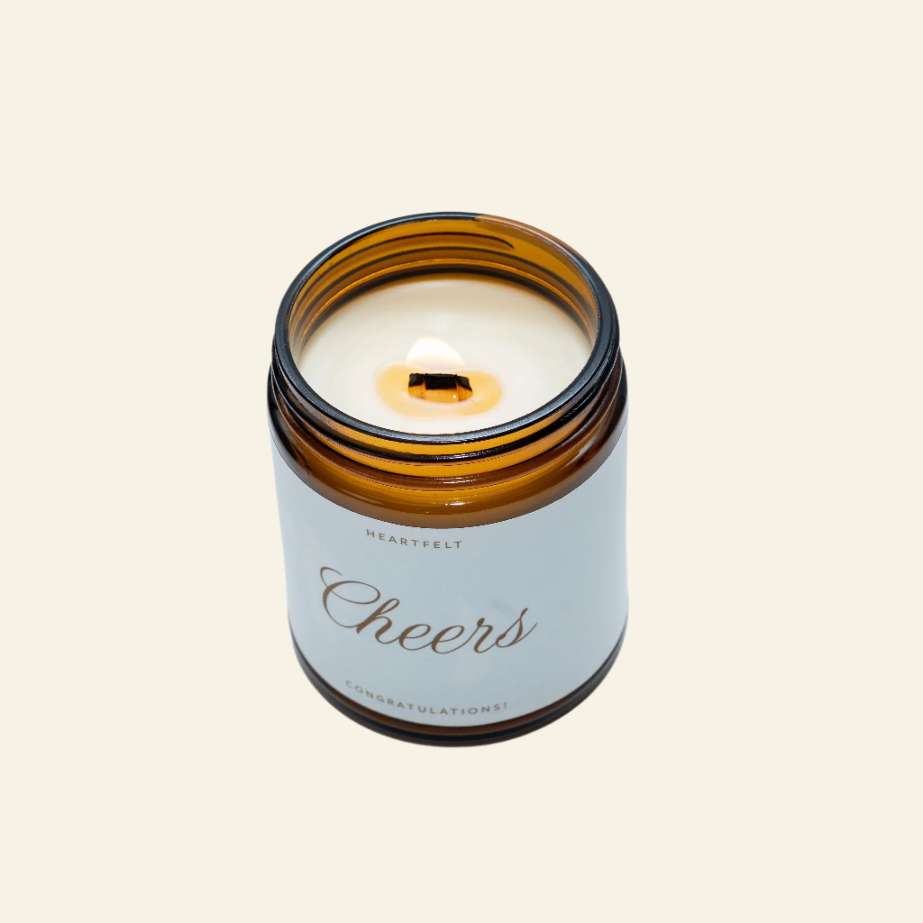 Candle in an amber glass jar with a white label on a light gray background