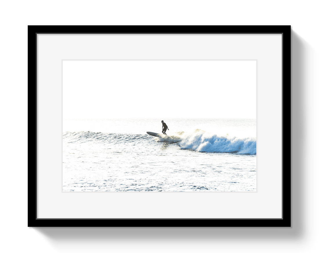 Framed photograph of a surfer riding a wave on a white background