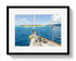 Framed photograph of a sailboat on a clear day with blue water and white clouds.