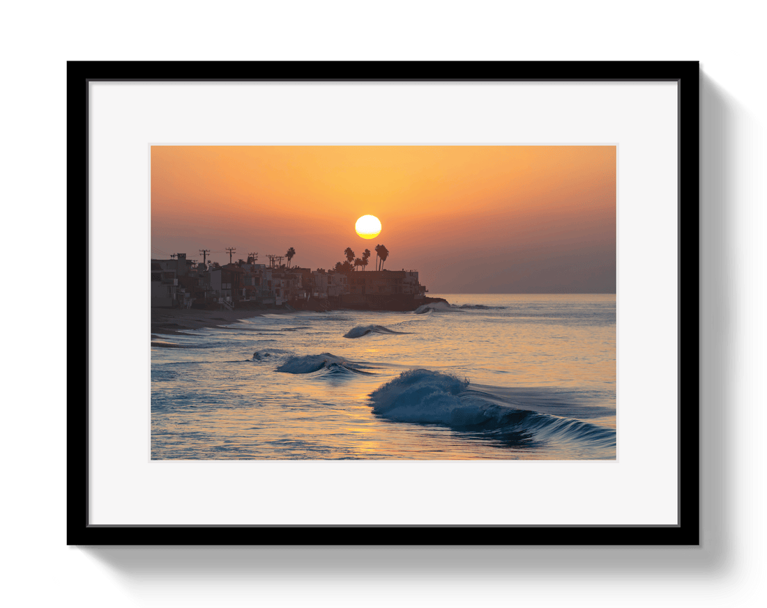 Framed artwork of a sunset over the ocean with a silhouette of buildings.