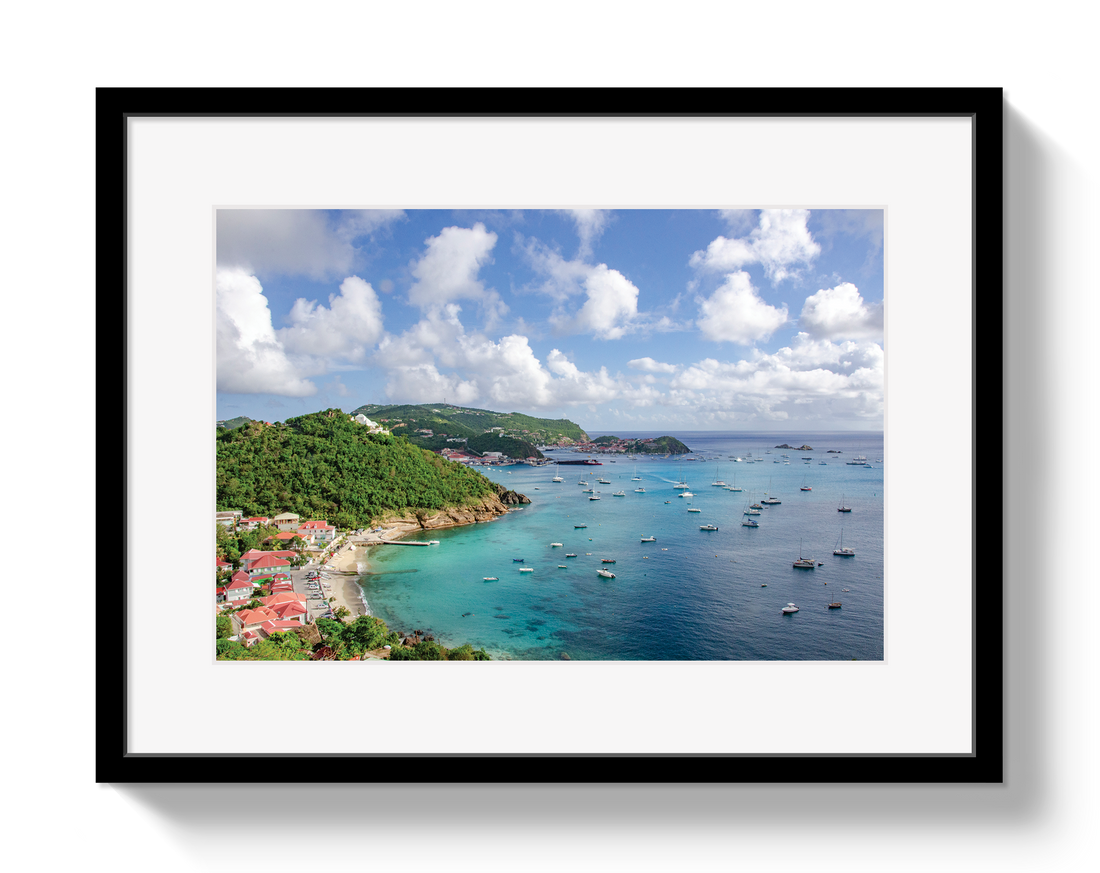 Framed photograph of a coastal scene with green hills, blue sea, and white clouds.